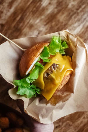 Close-up of a double burger. Adult fast food in a restaurant or cafe. Macro photo of burger ingredients with meat, cheese and herbs. Eco burgers for the whole familyの写真素材