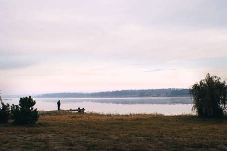 General plan of the pier for fishermen, which is located on a misty lake. The mist on the water creates the feeling of a magical effect. Clouds bounce off the surface. Place for textの写真素材