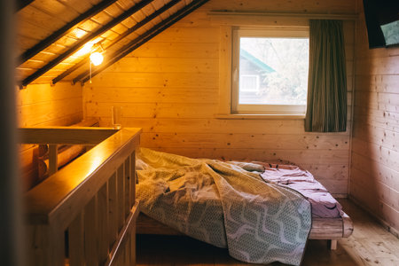 Wooden room in the attic in a country house. Double bed, sloped ceiling and young wood trim. The concept of relaxation and pleasant pastimeの写真素材