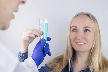 The dentist advises the girl on how to brush her teeth properly. The doctor teaches and explains. Isolated on white background. In the hands of a toothbrush and paste.の写真素材
