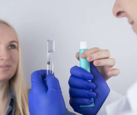 The dentist advises the girl on how to brush her teeth properly. The doctor teaches and explains. Isolated on white background. In the hands of a toothbrush and paste.の写真素材