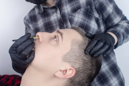 Removal of nose hair. Close-up of a man who gets unwanted hair removed by a specialist in a barber shop. Barbershop. Only for men. Male beauty salon concept.の写真素材