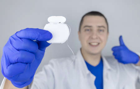Dental floss close up. Dentist shows how to use the thread correctly. Different types of flossing. The concept of proper oral care. selective focus.の写真素材