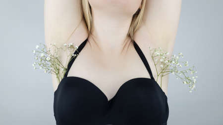 A woman has flowers sticking out under her armpits, symbolizing grown hair. concept photo. Body...