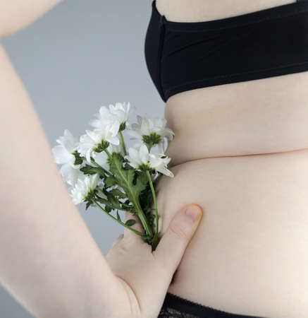 Close-up girl from behind. Side Pleats. Excess weight. Adoption non-ideal figure. Body positivity among women. concept shot. Flowers protrude from underpants, symbolizing acceptance one's appearance.の写真素材