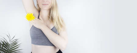 Concept of a pleasant smell from the armpits. Girl has yellow flowers sandwiched between her arms and chest. body care. women health. Chrysanthemums. Bodypositive and struggle for female naturalnessの写真素材
