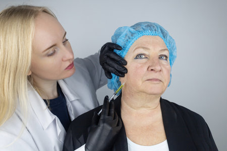Botulinum toxin injection. Senior woman at the appointment with a beautician who is preparing to give anti-wrinkle injections. Loose skin and hypotension. Mimic wrinkles and contouringの写真素材