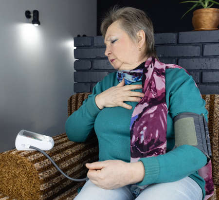 Senior woman measure blood pressure. Device for self-diagnosis and control of the heart. High or low...