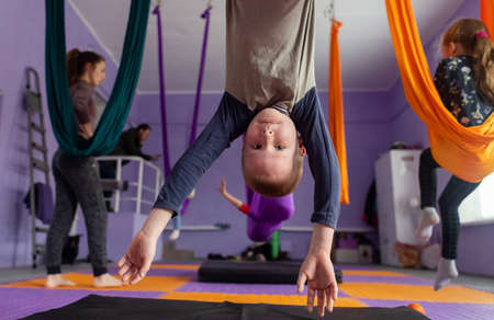 Fly yoga for kids. Kids and the coach are doing aerial acrobatics on cloth canvases. Parents and...