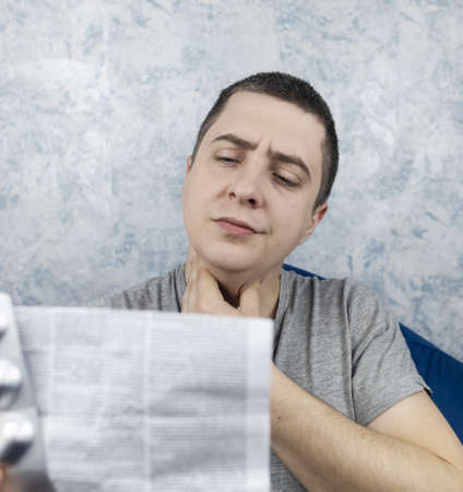 Man on a white background reads the instructions for medicines. Male looks at the list and...