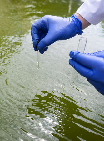 water sample. Checking the condition of rivers or natural lakes. Water test for chemicals, bacteria, harmful substances, radiation. Collection of material in a test tube for further research.の写真素材