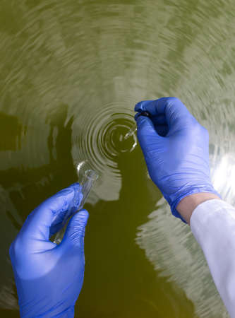water sample. Checking the condition of rivers or natural lakes. Water test for chemicals, bacteria, harmful substances, radiation. Collection of material in a test tube for further research.の写真素材