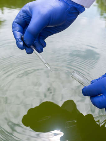 water sample. Checking the condition of rivers or natural lakes. Water test for chemicals, bacteria, harmful substances, radiation. Collection of material in a test tube for further research.の写真素材