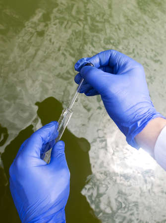 water sample. Checking the condition of rivers or natural lakes. Water test for chemicals, bacteria, harmful substances, radiation. Collection of material in a test tube for further research.の写真素材