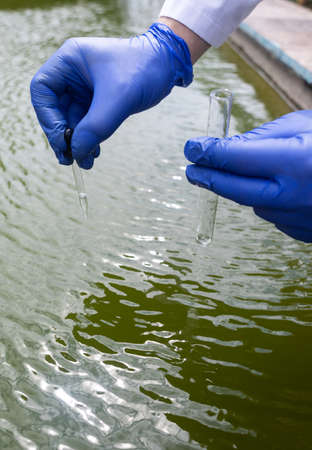 water sample. treatment facilities. Quality control of water that has been purified and processed. The laboratory assistant collects material for research. Liquid in a test tube. Sewage treatmentの写真素材