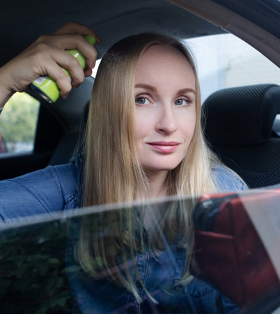 Dry shampoo. Blonde girl sprays shampoo on her hair. The problem of oily hair while traveling. An emergency remedy for excessive sebum production. Make your head clean without waterの写真素材