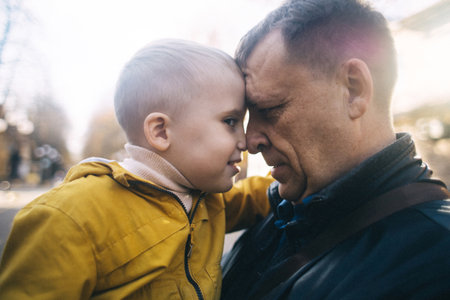 Dad and son in the park. A middle aged father holds his 4 year old son on his shoulders. The concept of caring parents. A happy child on the shoulders of a caring parent.の写真素材