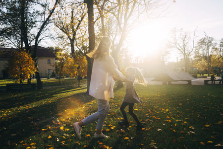 Mom and daughter in the autumn park. happy faces. Special lifestyle image processing. Sitting on the grass and yellowed leaves. Happy moments.の写真素材