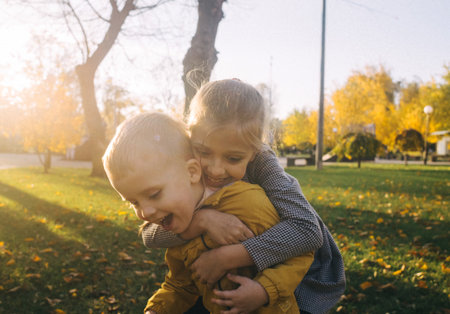 Brother and sister in the park. Boy and girl hold hands and run along the path of the park. The concept of happy childhood and heterosexual relations. Sunbeams and yellow leavesの写真素材