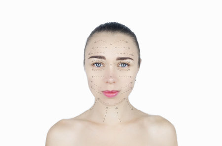 Girl shows massage lines on her face. Model runs her hands over her face, performing a rejuvenating massage procedure. Instructions on how to carry out the procedure are drawn with arrows. Cosmetologyの写真素材