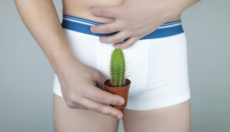 Prostatitis, inflammation of the bladder, cystitis, oncology, male problems, testicular cancer. Man in white shorts with concept symbols. Cutting during urination and pain. Man in white underwearの写真素材