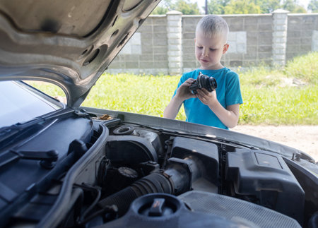 A mechanic dad teaches his son how to change the timing belt and car cooling pump at home. Child holds a pump in his hand. Maintenance of the car according to the regulations. new partsの写真素材