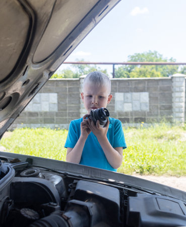 A mechanic dad teaches his son how to change the timing belt and car cooling pump at home. Child holds a pump in his hand. Maintenance of the car according to the regulations. new partsの写真素材