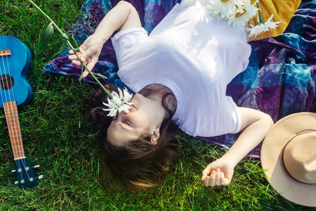 Woman lies on a purple blanket. On her body is a bouquet of daisies. Meditative state in a public...