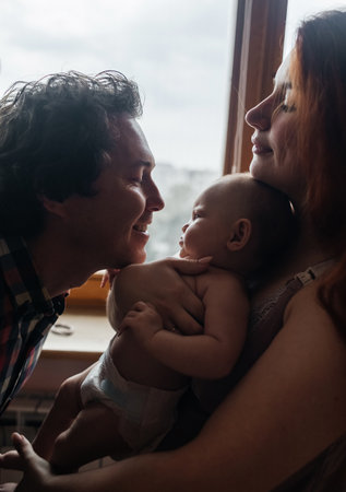 mom and dad newborn. Caring and loving parents kiss the child on both cheeks. The concept of loving...