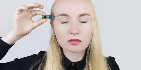 USB memory stick in head. Flash drive to brain. Girl stands with memory card in her hand and wants to insert it into her body. Cybernetization and rapid learning technologies. Improving your own mindの写真素材