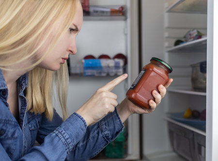 Woman reads instructions for food products at home. Checking labels on goods. Study of product compositions. Search Internet for descriptions of product gradients. Useful or harmful. Nutritionologyの写真素材