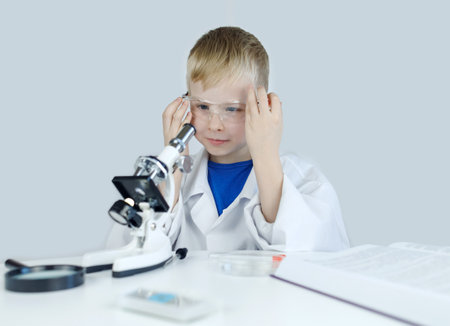 Child chemist. Teacher shows a visual experiment. A science mentor teaches an experimental approach. Microscope, petri dish, pipettes, books. Practical work in chemistry or physics. Laboratory workの写真素材