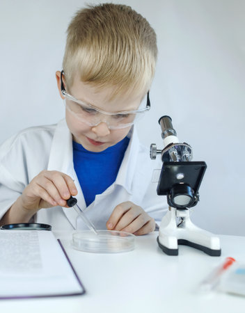 Child chemist. Teacher shows a visual experiment. A science mentor teaches an experimental approach. Microscope, petri dish, pipettes, books. Practical work in chemistry or physics. Laboratory workの写真素材