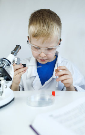 Child chemist. Teacher shows a visual experiment. A science mentor teaches an experimental approach. Microscope, petri dish, pipettes, books. Practical work in chemistry or physics. Laboratory workの写真素材