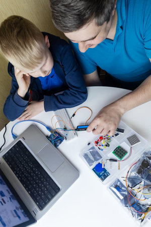 Programming for children. A teacher teaches a child at a robotics and IT school. Boy learning to code control boardの写真素材