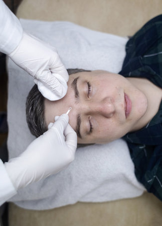 Man undergoing facial cleansing and blackhead removal. Beautician using comedone extractor or uno loop. Professional skin care in a beauty salonの写真素材