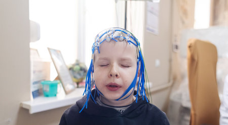 A boy's brain is examined on an EEG machine. Electroencephalogram is performed in a hospital laboratory to detect neurological diseases. Encephalogram for childrenの写真素材