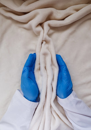 The hands of a medical professional support the folds of soft tissue. The concept of women's intimate health, prevention of gynecological diseasesの写真素材