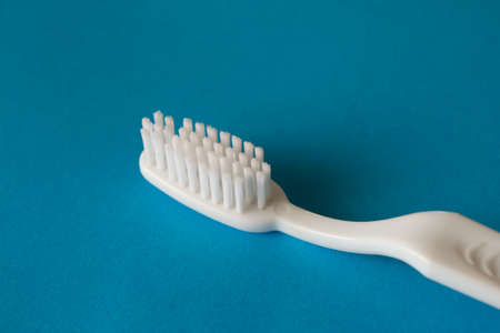 Close up macro plastic white tooth brush on blue background dental hygieneの写真素材