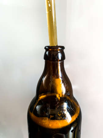 Craft beer brewery. Filling brown glass beer bottle at home. Self made beer. Close up vertical image...