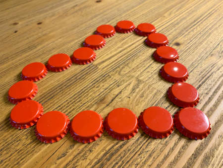 Red love heart made from beer bottle tops lids on a rustic wooden table. Beer drinkers Valentine's...
