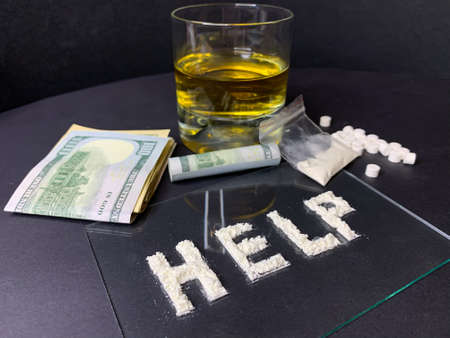 Pills; us dollar banknotes; whiskey and cocaine; on a gray background. Stop drugs concept. A word...
