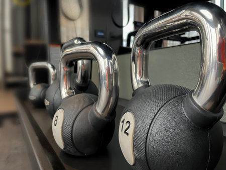Black 12 kg kettlebells on the gym shelve. Workout equipment closeup photo, no peopleの写真素材