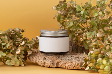 Cosmetic product mockups on stone and natural tree branches on yellow background. Trendy cosmetics concept.の写真素材