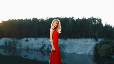 Portrait of a beautiful woman in a red dress on a mountain near the riverの写真素材