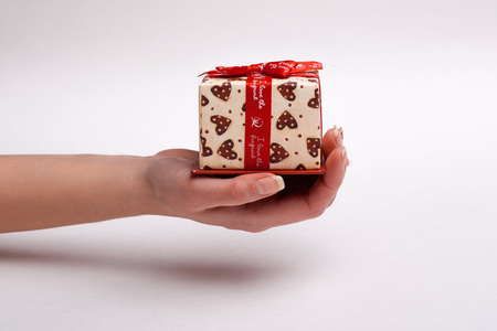 Woman's hand gives a beautiful gift box with a bow.の写真素材