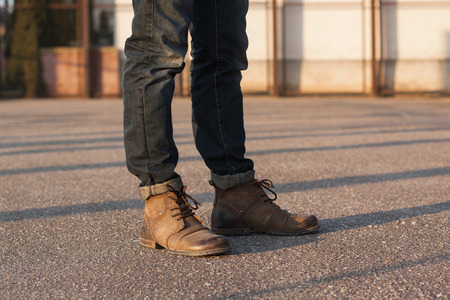 Men's legs with jeans and boots. Hipster at sunset.の写真素材