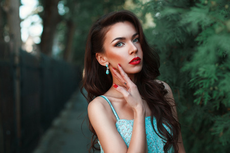 Fashion portrait of a beautiful woman in a turquoise dress in the park.の写真素材