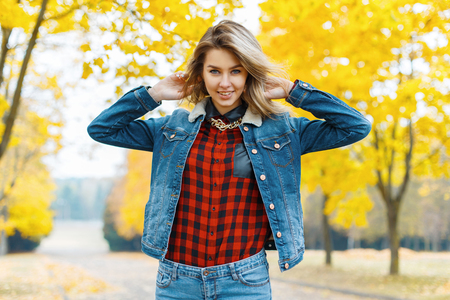 Young woman in jeans clothes in the autumn park.の写真素材