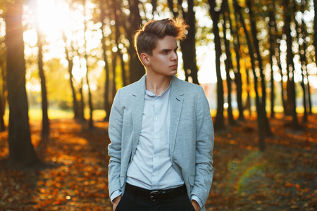 Young urban businessman professional walking in park at sunset.の写真素材